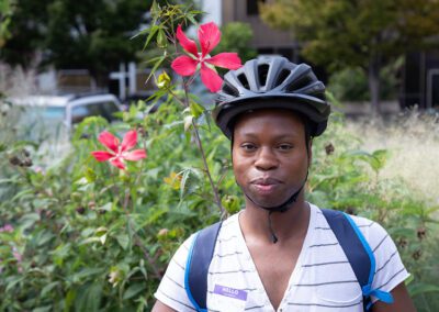 A person wearing a helmet standing next to flowers.