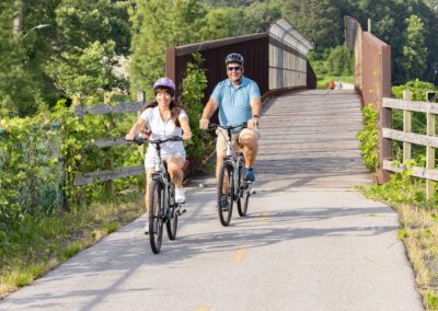 Two people riding bikes on a bridge over water.