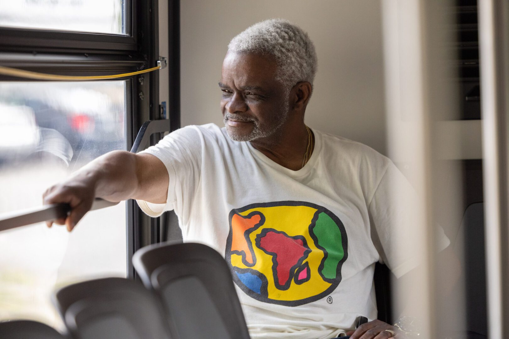 A man sitting on top of a bus looking at the window.