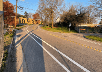 A street with no traffic on it and trees in the background.